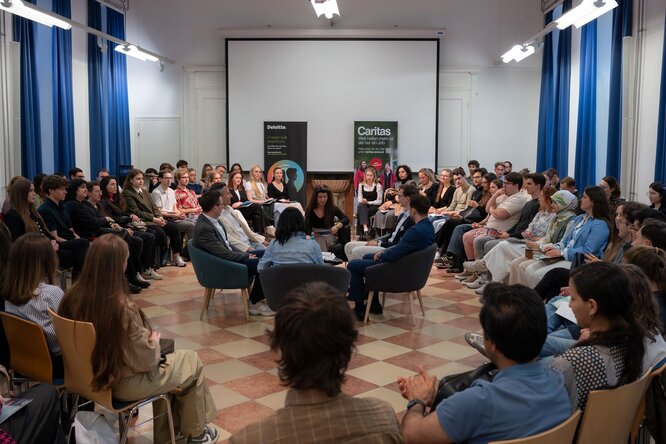 Diskussionsrunde in einem großen Saal, das Publikum sitzt rund um die Diskutierenden.